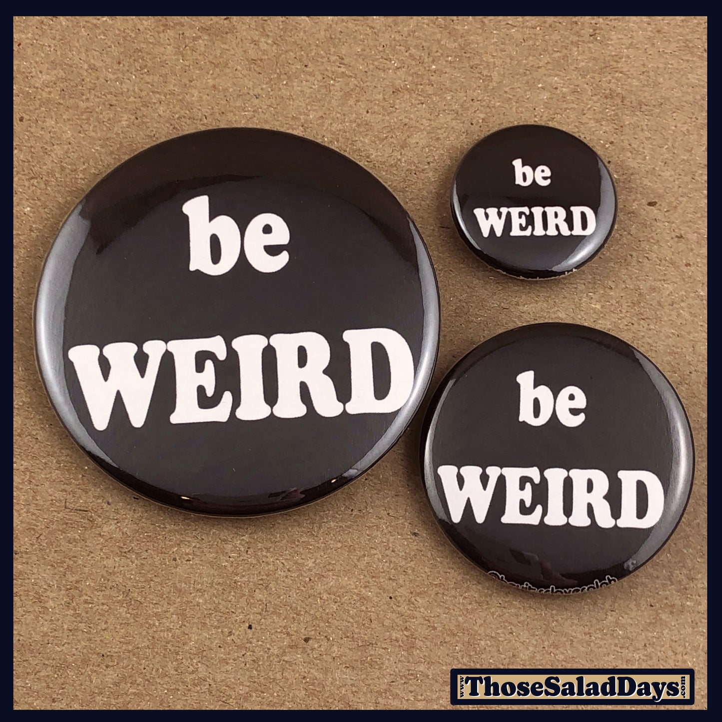 Three 'be WEIRD' buttons on a textured brown background