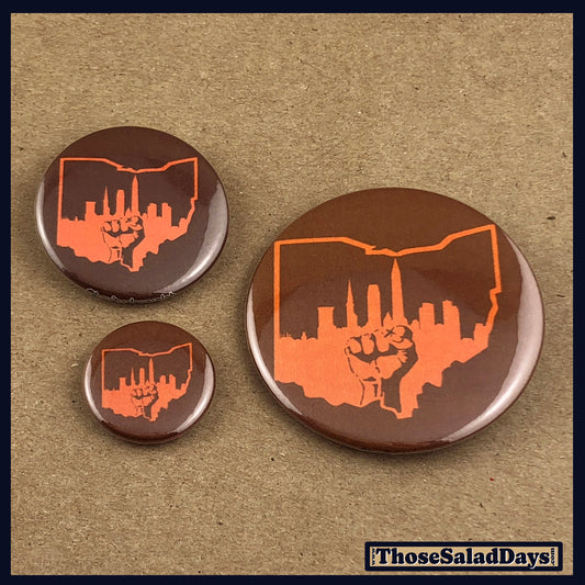 Three buttons with the cleveland city skyline and power fist design