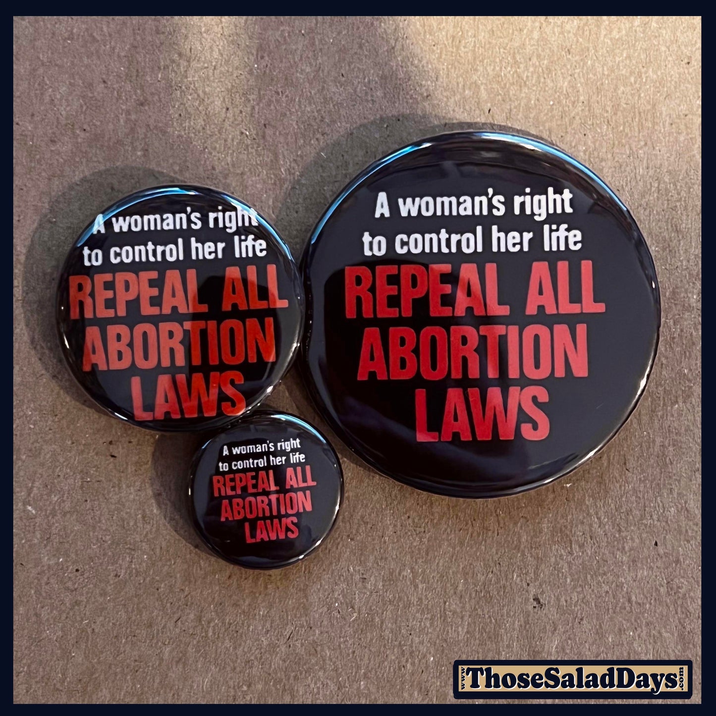Three buttons with pro-choice text on a cardboard background