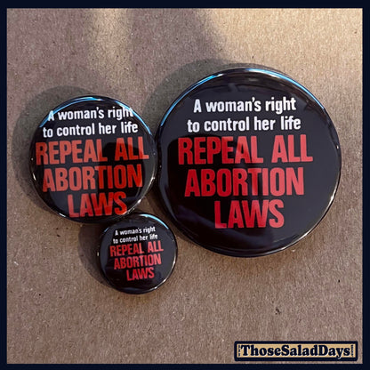Three buttons with pro-choice text on a cardboard background
