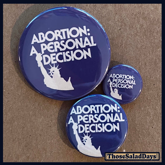 Three blue buttons with 'Abortion: A Personal Decision' text and Statue of Liberty silhouette on a brown background.