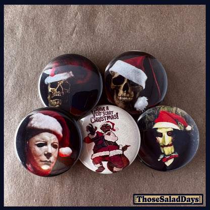 Set of five buttons with Halloween and christmas themed designs featuring skulls and masks with Santa hats