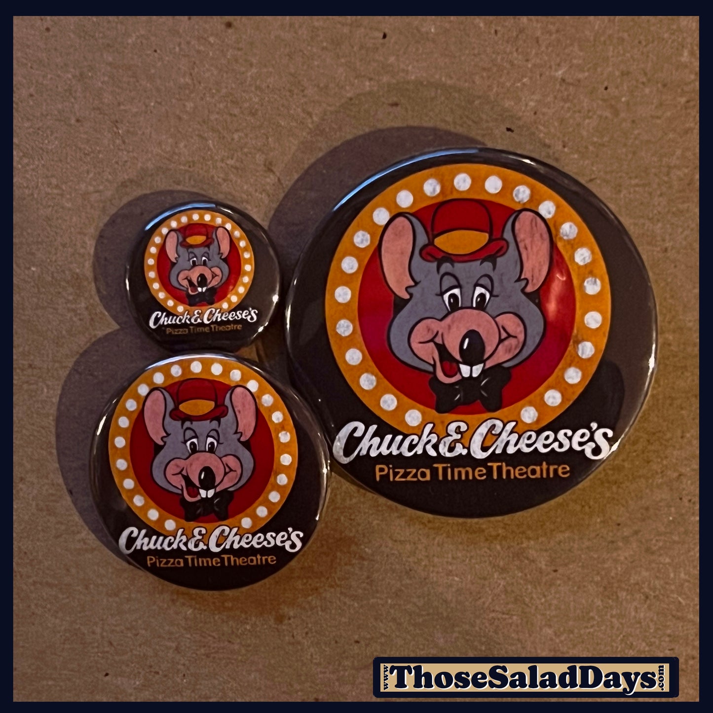 Three Chuck & Cheese's logo buttons on a brown background