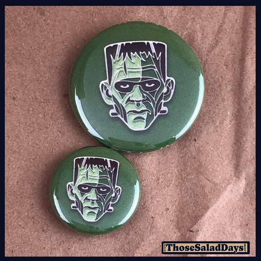 Two buttons of a colorful monster. One size is 1" and the other is 1.5".