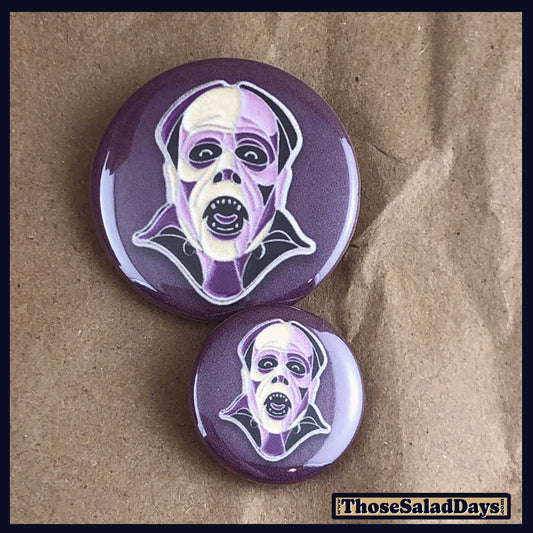 Two buttons of a colorful monster. One size is 1" and the other is 1.5".