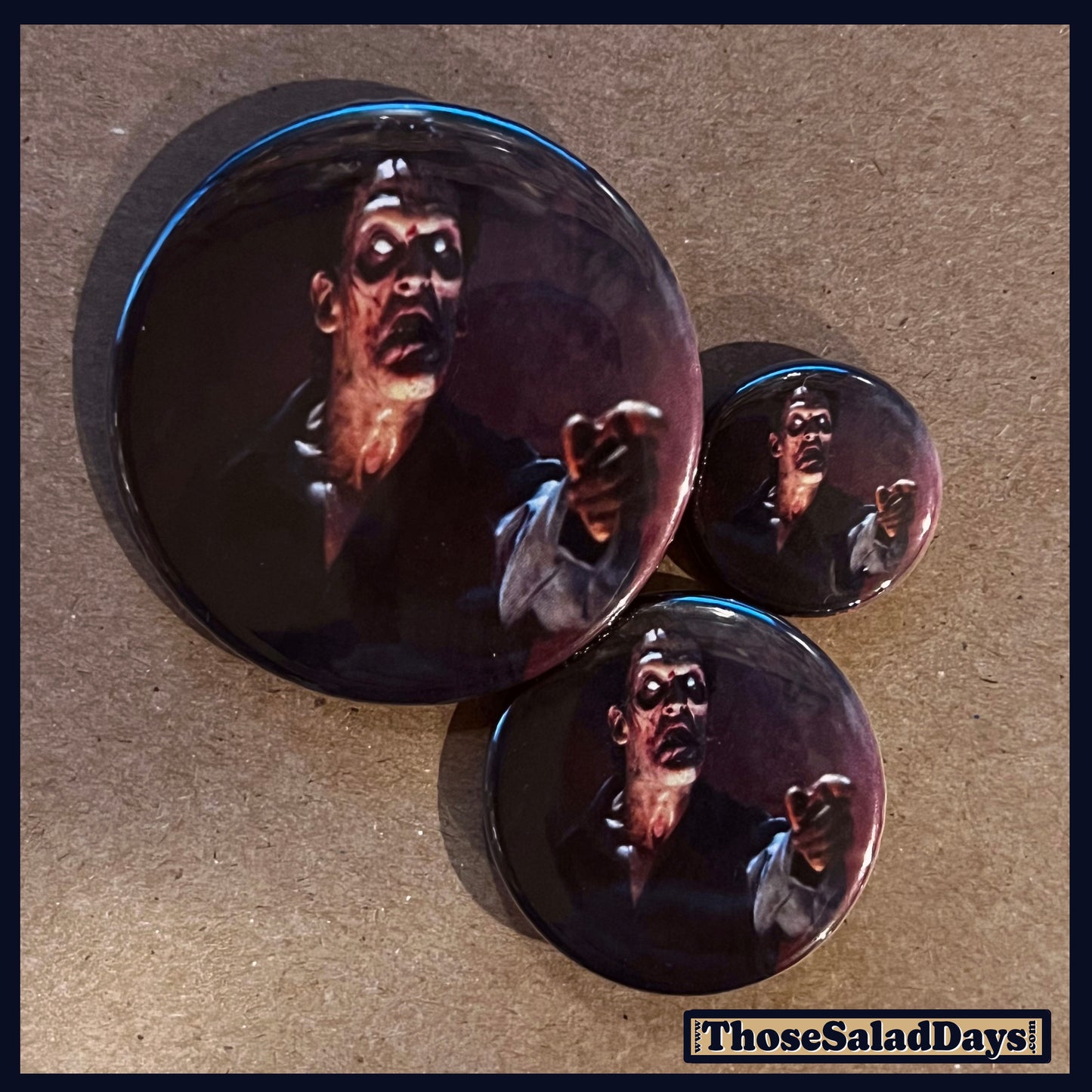 Three buttons of an Evil Dead type image. One size is 1", 1.5" and 2.25".