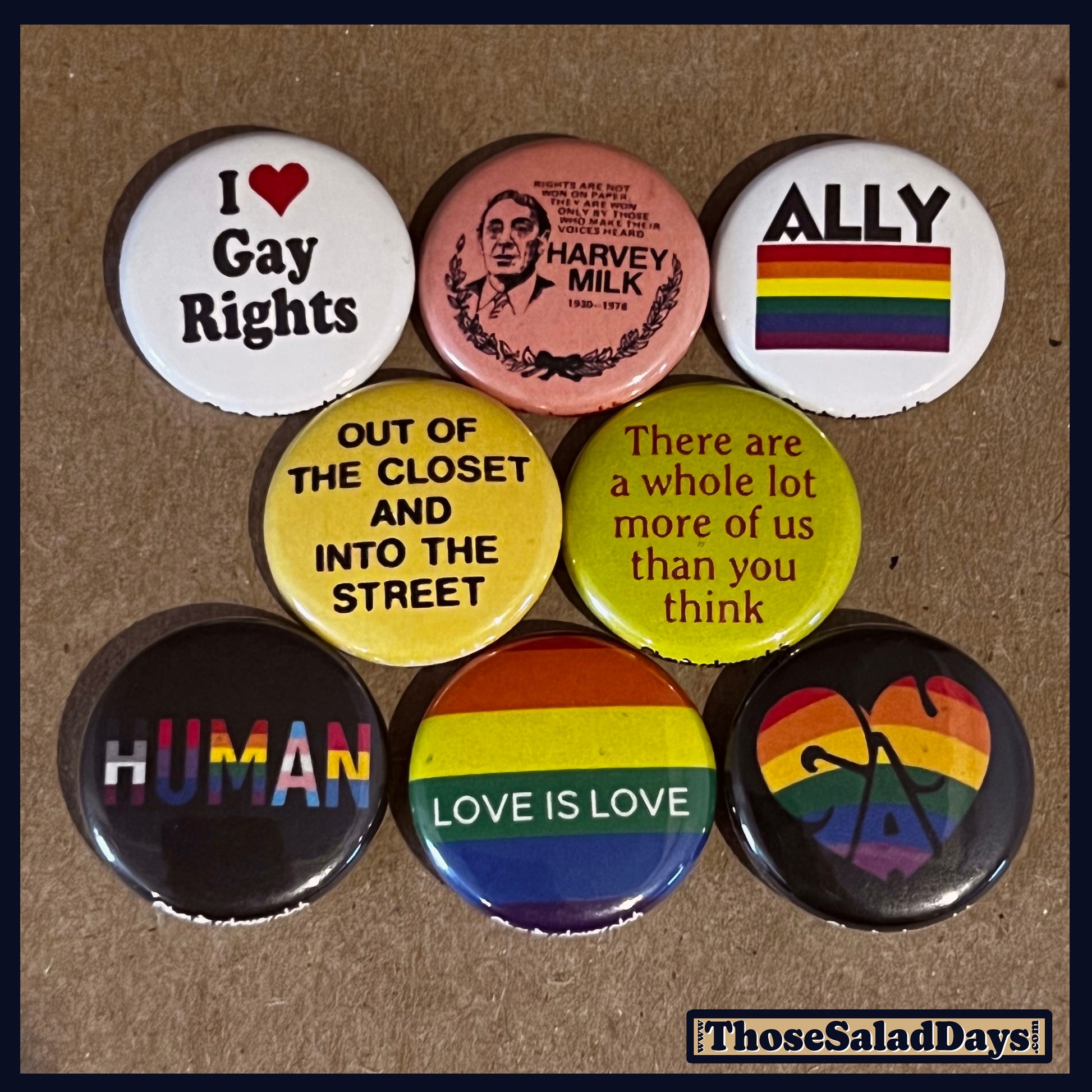 Collection of LGBTQ+ themed buttons on a cardboard background