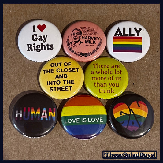 Collection of LGBTQ+ themed buttons on a cardboard background