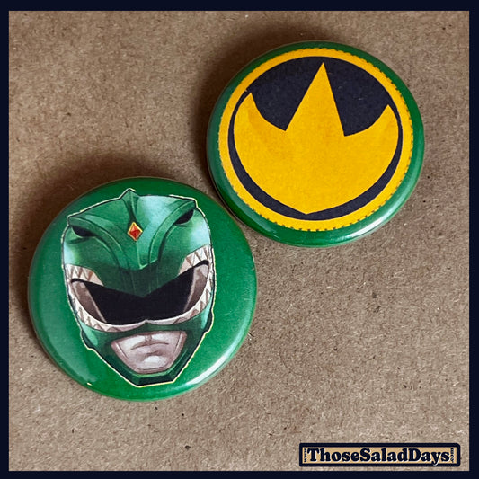 Two buttons featuring a helmet design and dino logo like the Green Power Ranger on a brown background.
