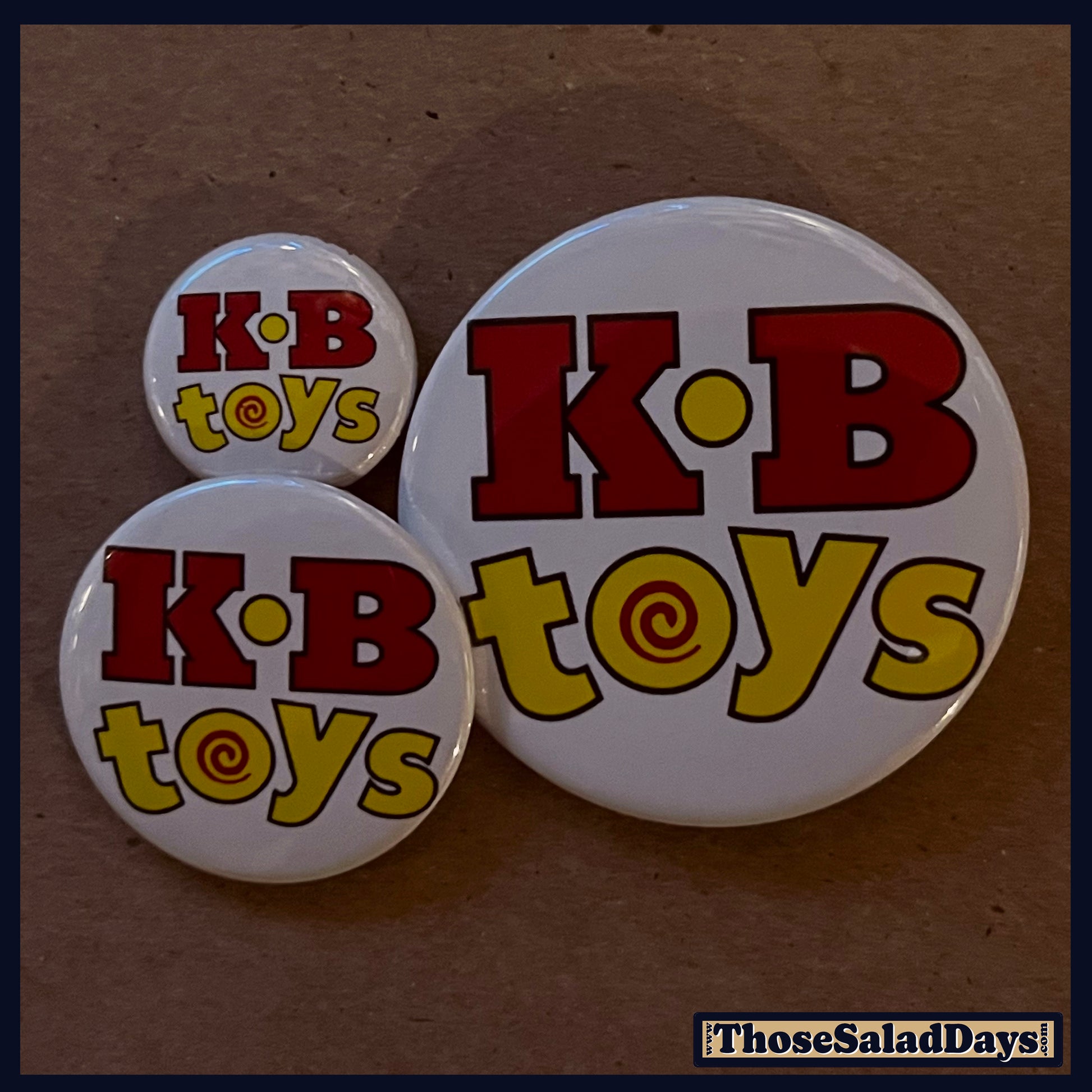 Three 'K.B toys' buttons on a brown background