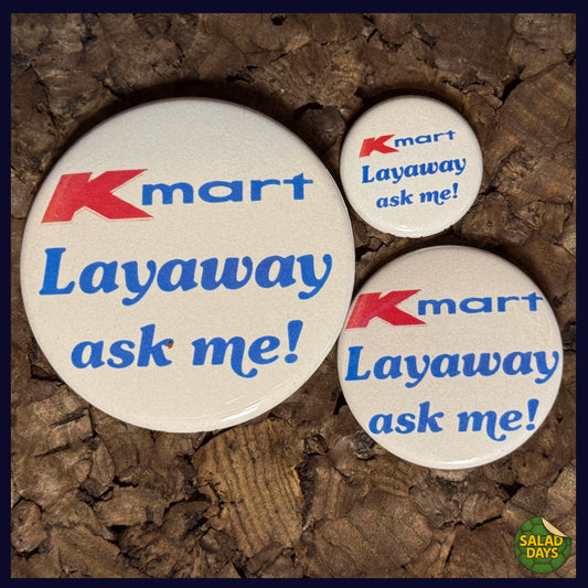 Three Kmart layaway promotional buttons on a textured brown background