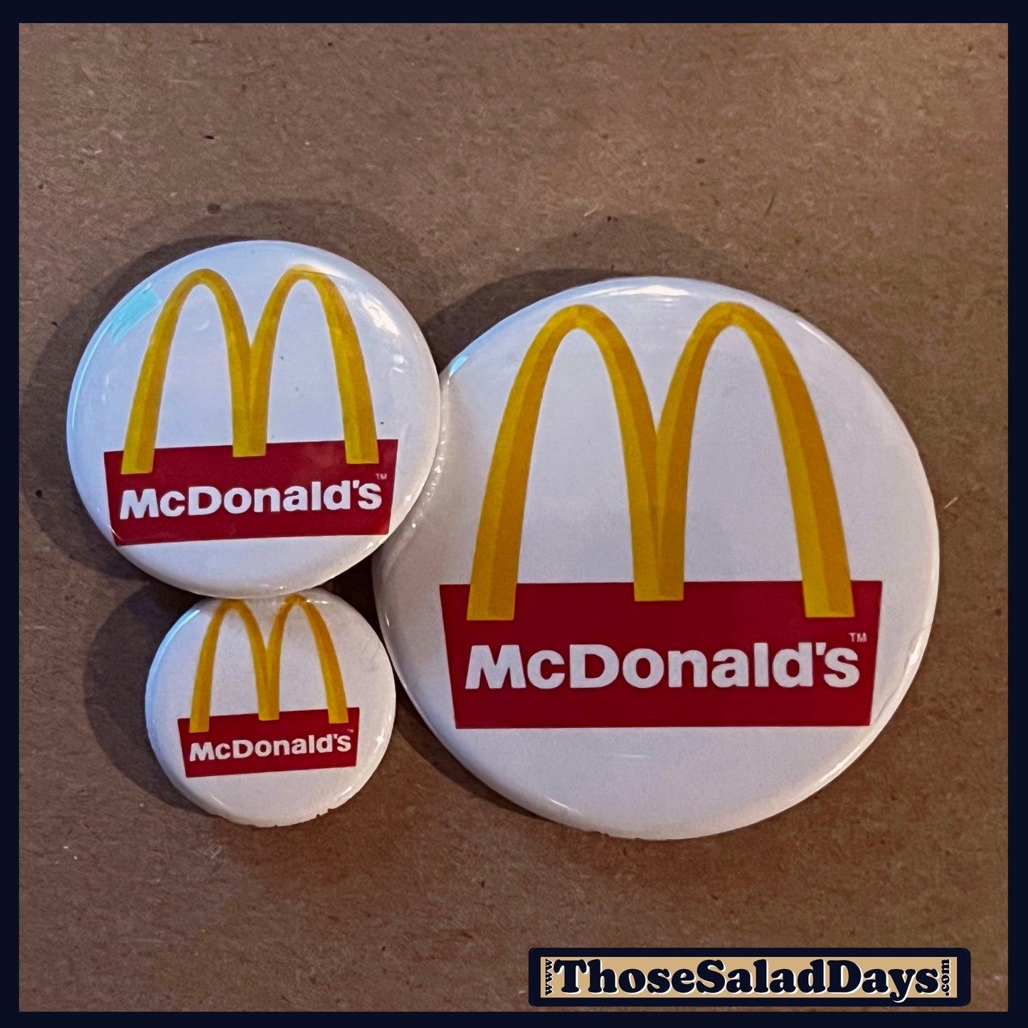 Three McDonald's logo buttons on a brown background.