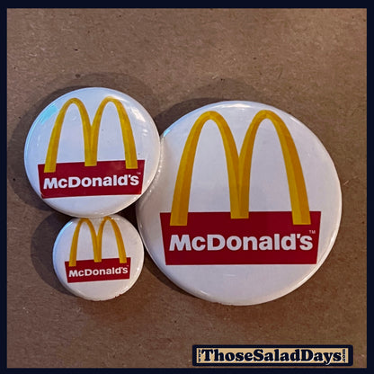 Three McDonald's logo buttons on a brown background.