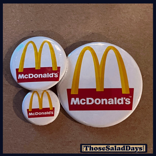Three McDonald's logo buttons on a brown background.