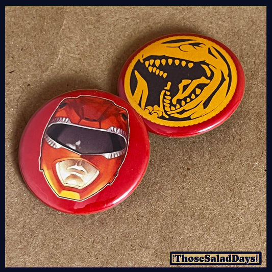 Two buttons featuring a helmet design and dino logo like the Red Power Ranger on a brown background.