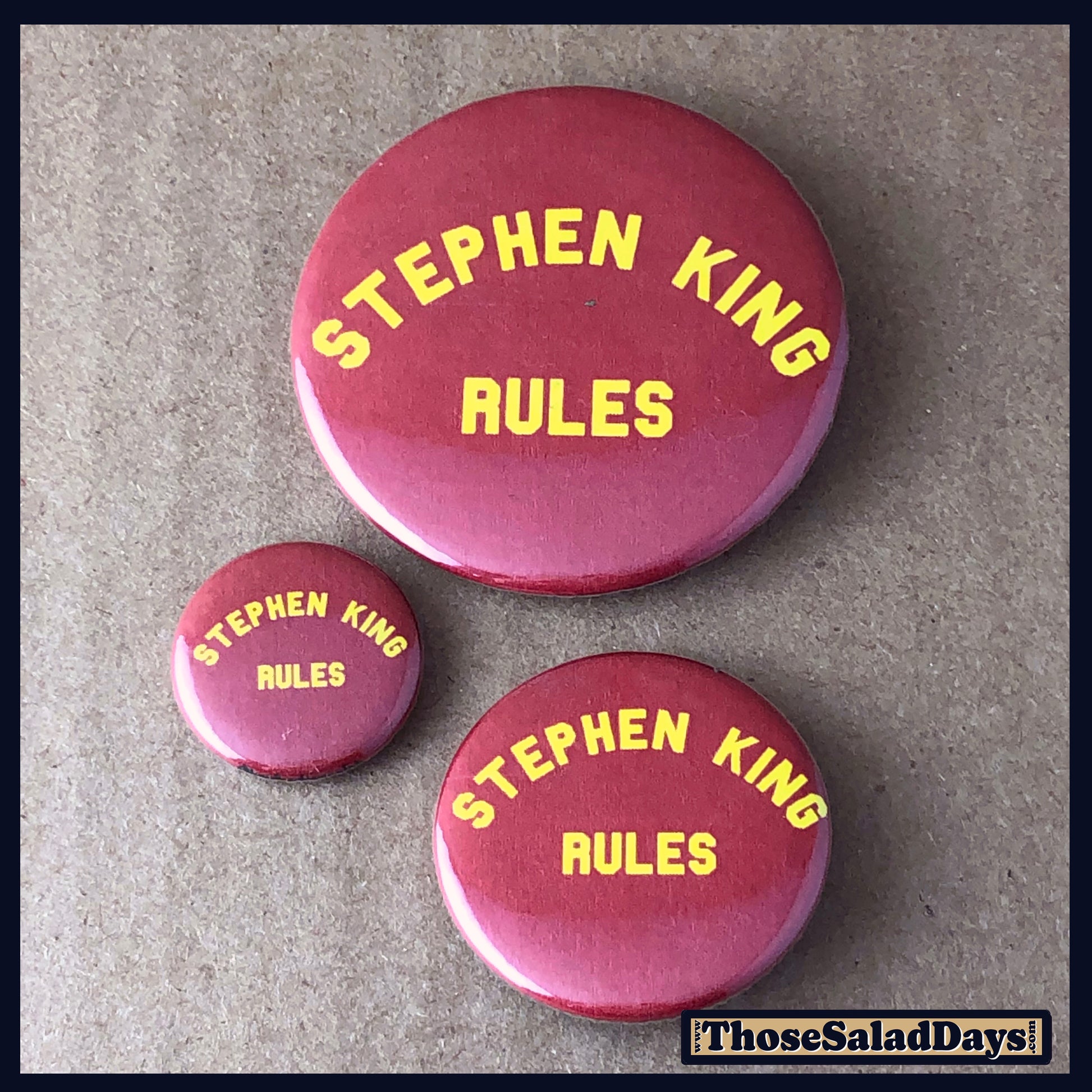 Three 'Stephen King Rules' buttons on a textured surface 