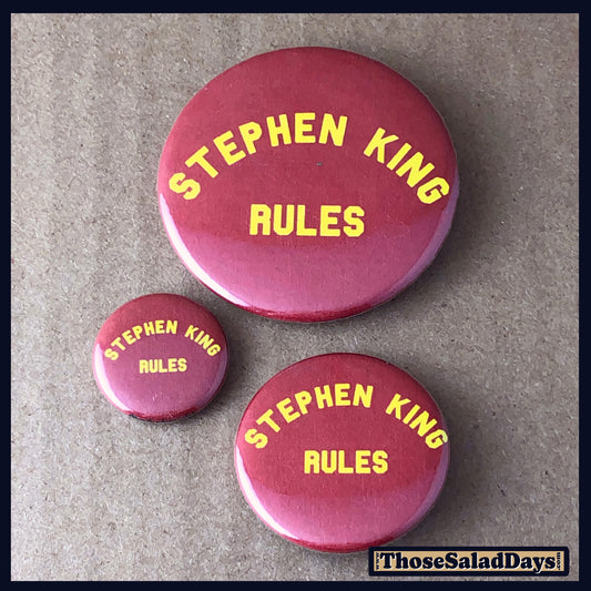 Three 'Stephen King Rules' buttons on a textured surface 