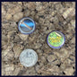 Two buttons on a textured surface with a quarter for scale. Showing the size of the button is 1 Inch.