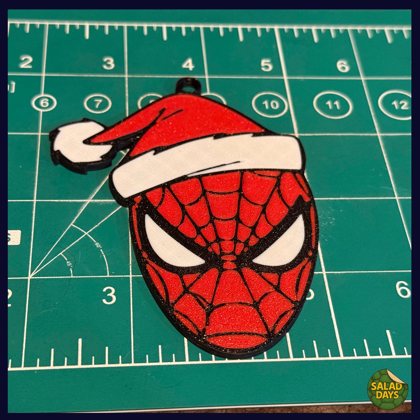 Spider-Man mask with Santa hat on a green cutting mat
