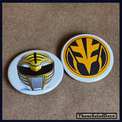 Two buttons featuring a helmet design and dino logo like the White Power Ranger on a brown background.