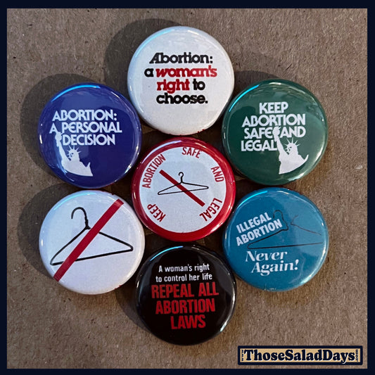 Collection of buttons with pro-choice messages on a brown background.